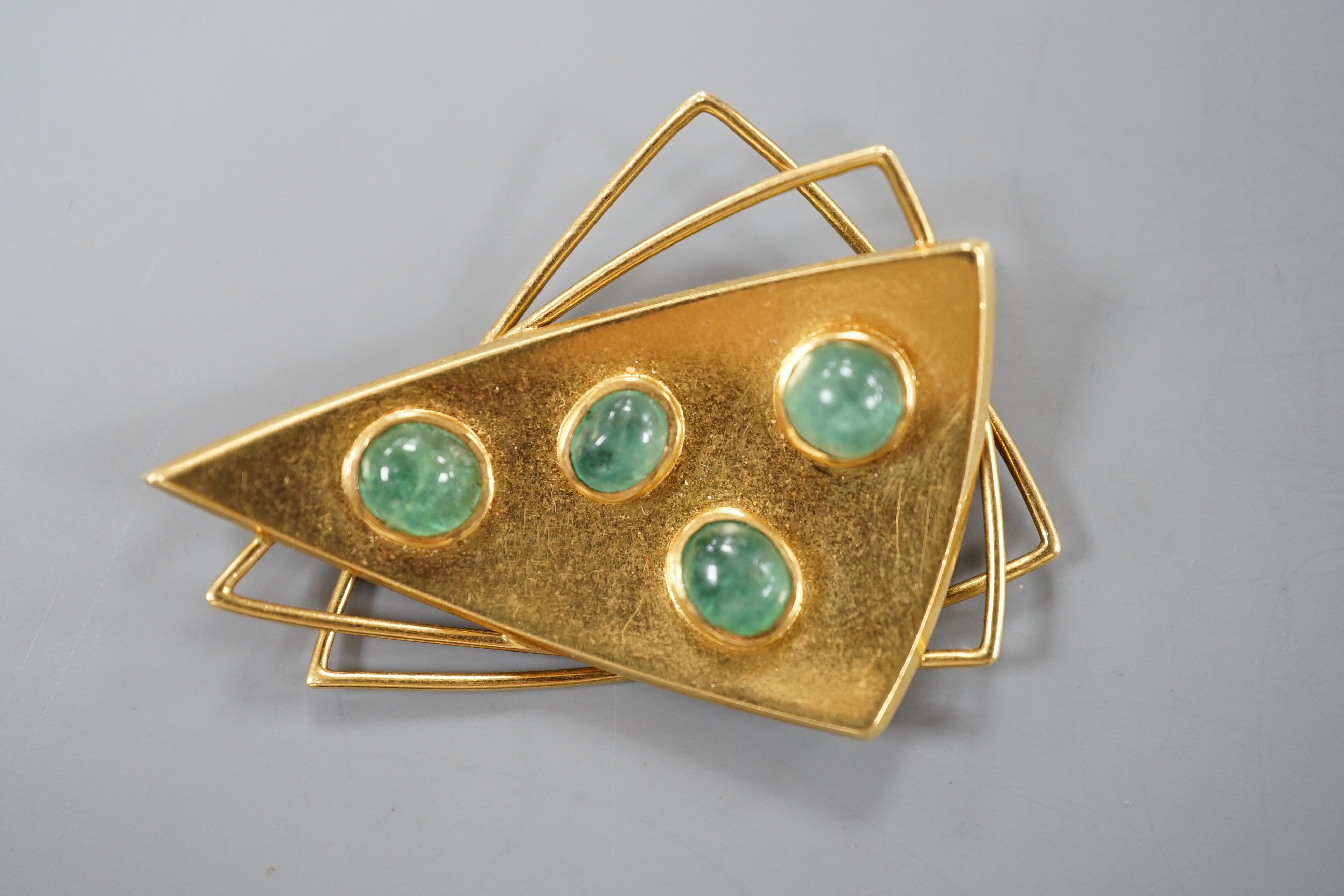 A stylish continental 750 yellow metal triple triangle brooch, mounted with four cabochon emeralds, 43mm, gross weight 9.6 grams.